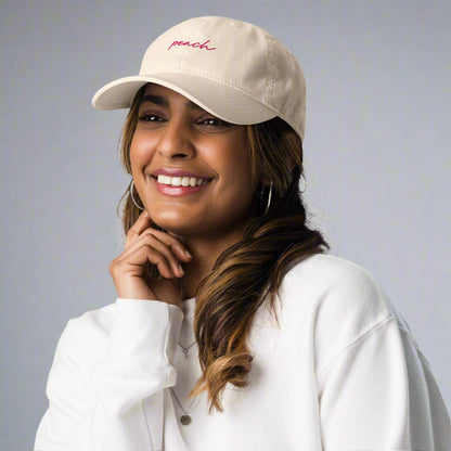 Tan baseball cap with pink Peach embroidery on model