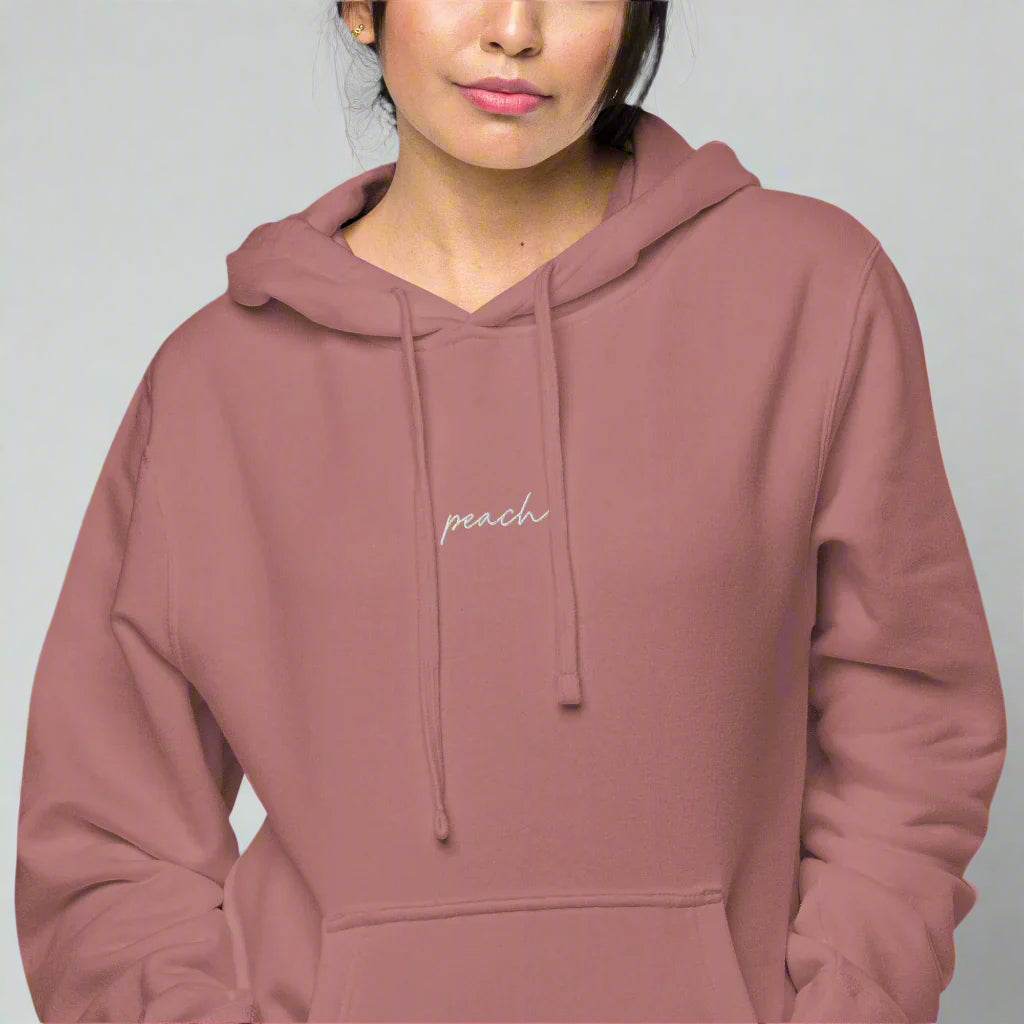 Model wearing hoodie with peach embroidered on the front